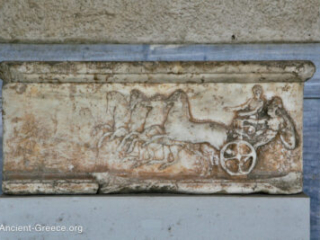 Base of a sculpture with a relief carving depicting a man getting on and off a chariot