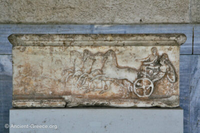 Base of a sculpture with a relief carving depicting a man getting on and off a chariot