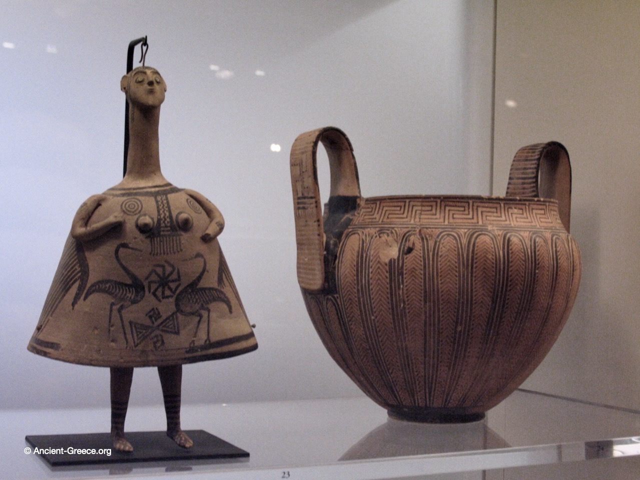 Ceramic vessel and figurine in display case