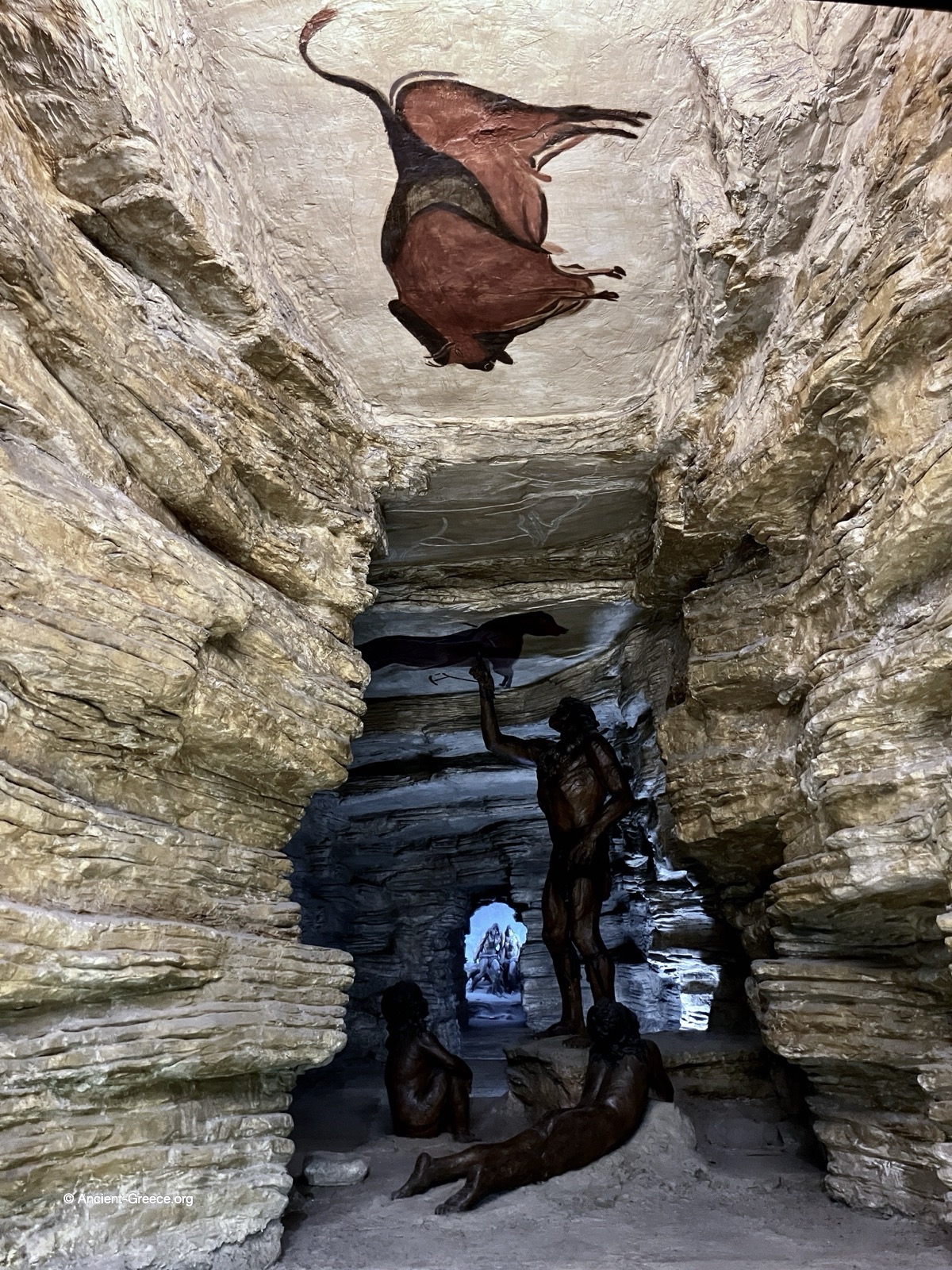 Museum replica of Stone Age people painting a cave ceiling.
