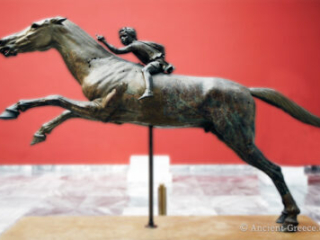 Bronze statue of a young jockey on a leaping horse.