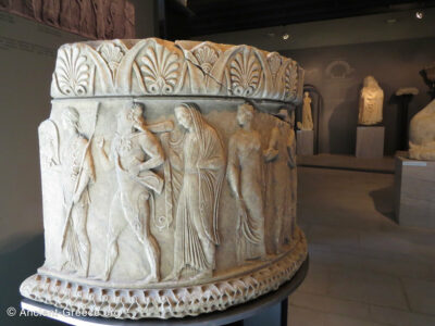 Semi-circular marble base with relief scene of gods